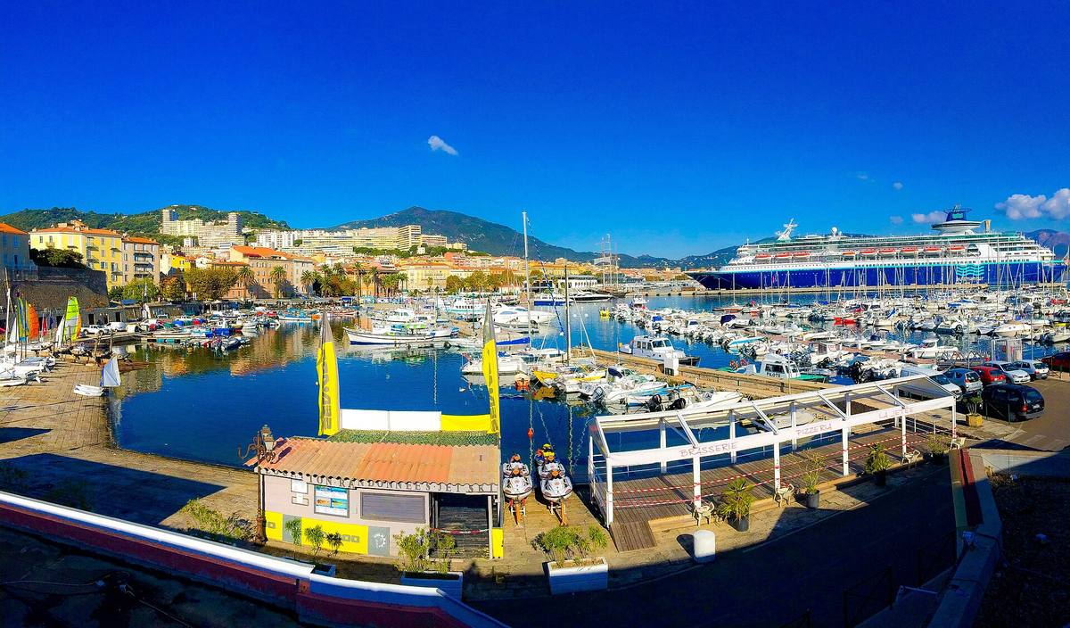 Le port Tino-Rossi d'Ajaccio avec ses bateaux de plaisance, les immeubles de la ville et les montagnes en arrière-plan