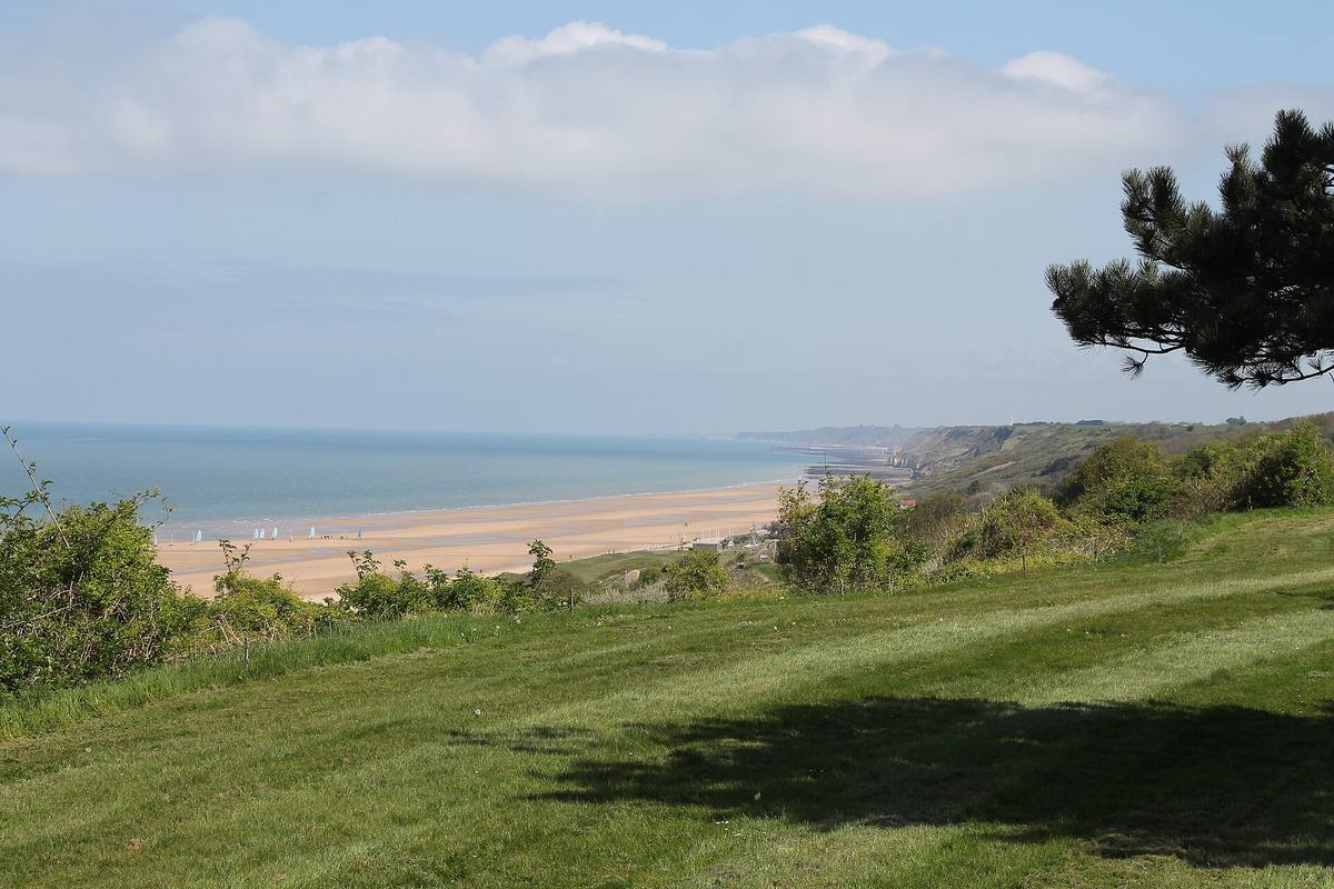 La longue plage de sable d'Omaha Beach vue depuis les hauteurs herbeuses du cimetière américain de Colleville-sur-Mer