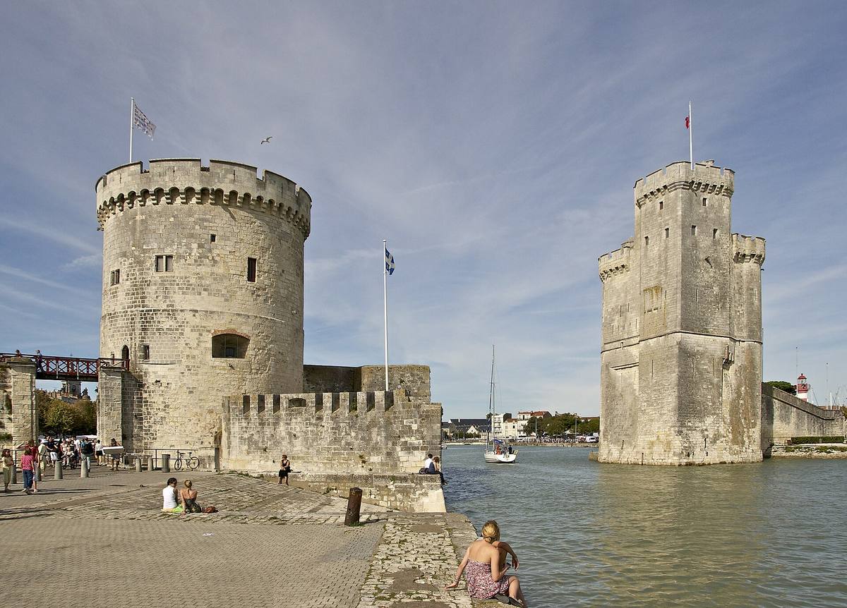 La tour de la Chaîne et la tour Saint-Nicolas encadrant l'entrée du Vieux-Port de La Rochelle, un voilier passant entre elles